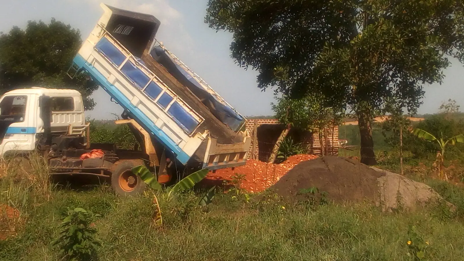 Camión de volteo descargando arena en un terreno de obra