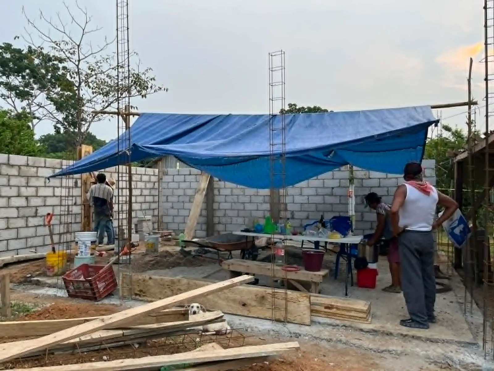 Casa en obra negra en México: muros de block, castillos de varilla y lona azul sobre el área de trabajo